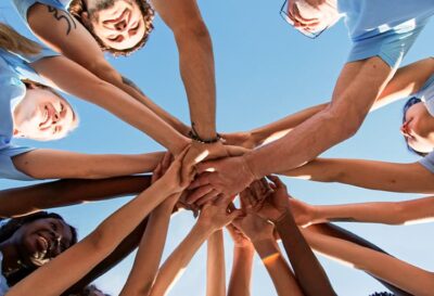 Several People Putting Their Hands Together In A Circle To Show Teamwork And Community