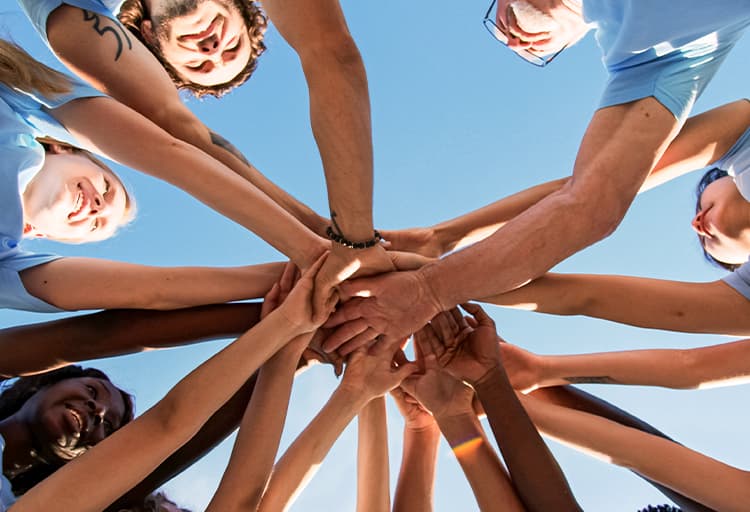 several people putting their hands together in a circle to show teamwork and community