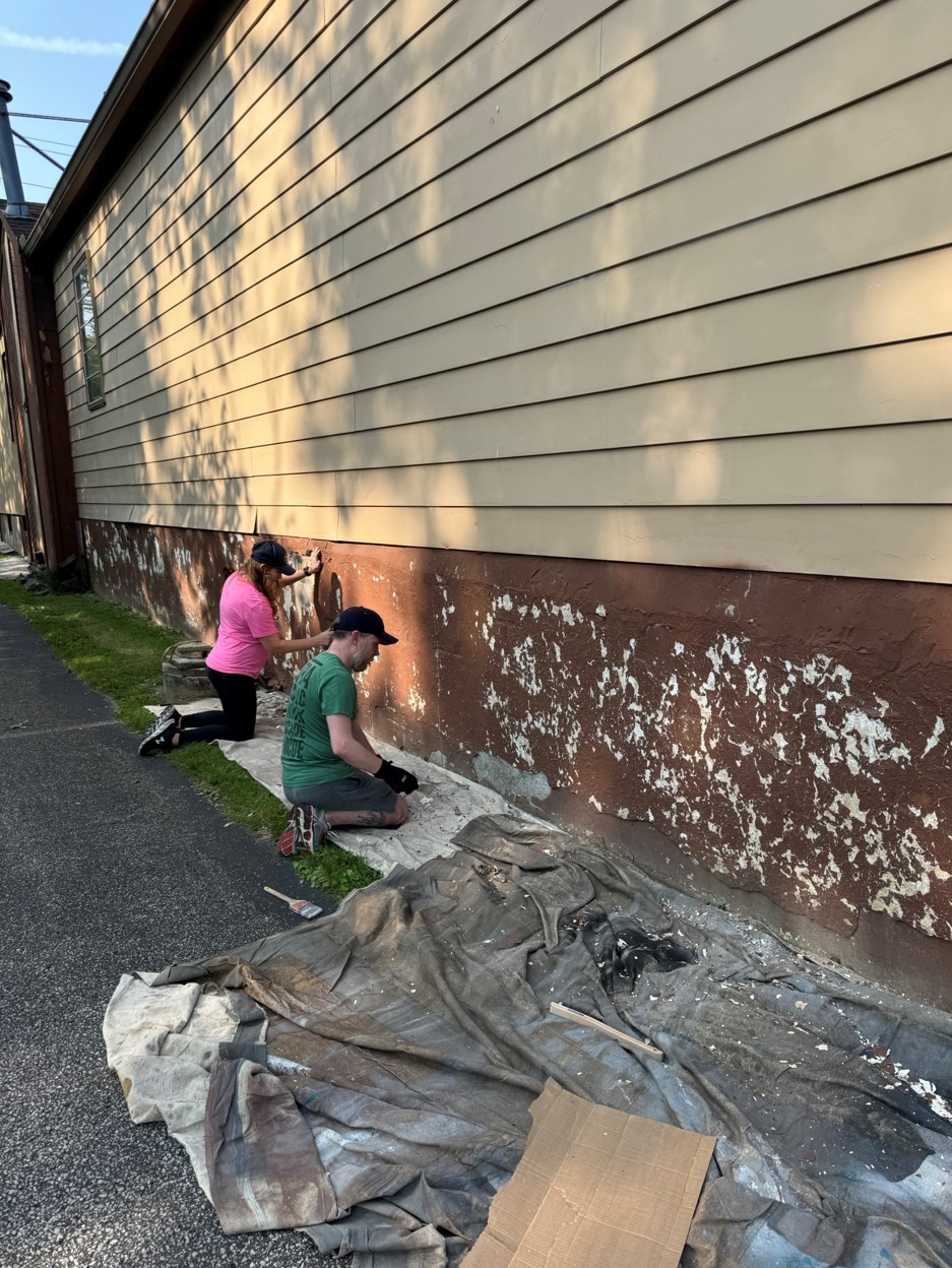 Volunteers scraping and painting during a community repair day